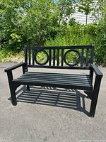 Front view of the black folding wood bench showing the full bench structure, two circular backrest cutouts, armrests, and slatted seat.