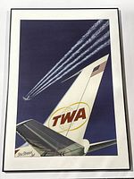 Framed 1960s TWA airplane poster showing the tail of a Star Stream Jet with contrails in a blue sky. Close-up of the TWA logo and American flag on the tail.