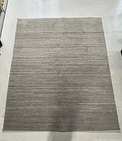 Top-down image of the full large rectangular grey marled rug laid flat on white floor showing the subtle horizontal stripes and blended grey tones