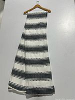 Full view of the folded duvet cover hanging on a wooden hanger against a white wall, showing the alternating wide black and ivory stripes.