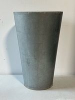 Front view of the tall galvanized metal planter showing its tapered cylindrical shape and metal surface.