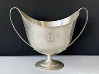 Overall front view of silver-tone metal ice bucket with twin handles and footed base