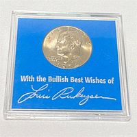 Obverse side of 1976 Eisenhower Dollar showing the profile of Eisenhower and text with Louis Rukeyser's signature in a clear plastic case.