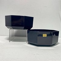 Two black octagonal glass serving dishes, one raised on stand, one with Arcoroc France label visible.