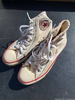 Right and left side view of both cream high-top Converse sneakers showing baseball themed stitching and logo patches.