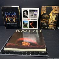 Four books displayed side by side on a black surface with a measuring ruler visible. Titles are Edgar Allan Poe Complete Tales & Poems, The Great LIFE Photographers, The Picture of Dorian Gray, and Karsh.