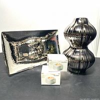 Abstract chrome vase, rectangular hammered tray, and two boxed candle holders together