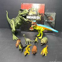 Photo of entire lot showing all dinosaur figures, original book, and VHS tape