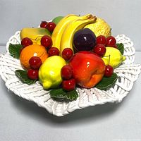 Top-down view showing all ceramic fruits arranged inside the white woven ceramic basket.