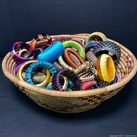 View of large woven basket filled with colorful silk and leather bangles and bracelets.