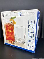 Box of Libbey Squeeze 12-piece glassware set, showing front with image of two highball glasses, one filled with iced tea and garnished with a lemon wedge.