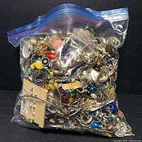 Large resealable plastic bag filled with assorted jewelry parts and pieces including clasps, beads, rings, and earrings.