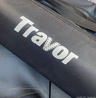 Close-up photo of black carrying bag with 'Travor' logo printed on it in white lettering.