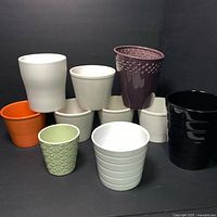 Photo showing 10 planters of various colors and shapes arranged together on dark background.