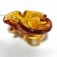 Photo of small amber glass trinket dish showing the folded organic shape and warm translucent amber color.