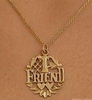 Close-up front view of the 10K gold pendant on a chain showing the '#1 FRIEND' design with decorative leaves and hearts.