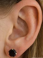 Earring worn on ear showing size and style of round garnet stud in 10K gold setting.