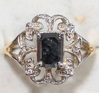 Overhead view of ring on white background showing black emerald cut center stone and filigree design
