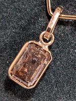 Close-up photo of the rectangular pendant with light brown diamond showing inclusions set in 10K gold.