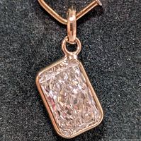 Close-up view of rectangular radiant cut diamond pendant set in 10K yellow gold bezel on black background