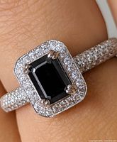 Ring worn on finger showing central black diamond and surrounding CZ halo