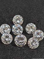 Close-up photo of seven loose round cut cubic zirconia stones on a black background, showing clarity and faceting to highlight sparkle and cut.