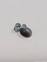 Four loose genuine alexandrite gemstones on white background, showing different cuts and colors.