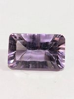 Top view of a rectangular cut, genuine amethyst showing its pale purple color, cut facets, and internal clarity.