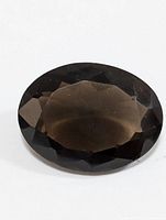 Close-up image of the oval faceted smokey quartz gemstone showing dark brown translucent color and faceted surface.