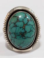 Front view of the sterling silver ring with a large turquoise cabochon stone and detailed bezel.