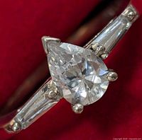 Close-up front view of the sterling silver ring showing pear-shaped cubic zirconia center and baguette CZ side stones.