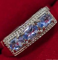 Close-up front view of the ring showing three oval tanzanite stones set in silver with beaded silver border.