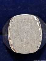 Front view of silver ring showing brushed rectangular top with beveled edges.