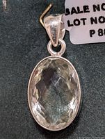 Close-up front view of oval faceted green amethyst silver pendant, showing gemstone clarity and setting.