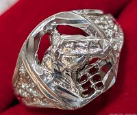 Close-up view of sterling silver ring face showing detailed horse head and open lattice design on red background.