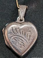 Front view of silver heart-shaped locket pendant with engraved floral design