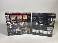 Front view of two sealed VHS box sets: the Band of Brothers 6-VHS and the Frank Capra WWII Special Edition 7-VHS set.