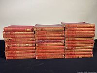 Front view of 30 red leather-bound Chronicles of Canada volumes stacked in three rows showing spine details and uniform size.
