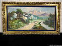 Full view of the framed oil painting showing the landscape scene with house, trees, mountains and figure.