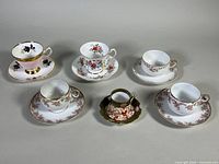 Front view of all five demitasse teacups and saucers showing various floral and decorative patterns.