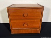 Front view of the MCM teak veneer side/end table showing two wooden drawers with round knobs.