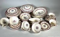 Overview of whole set including covered serving bowl, gravy boat, plates, bowls, and cups in floral and red decorative patterns