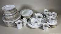 Overall view of all plates, bowls, mugs and serving pieces arranged on table.