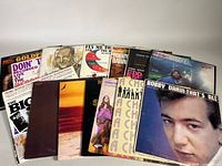 Photo showing a collection of vintage vinyl record album covers stacked and slightly overlapped, featuring various artists and soundtracks including Bobby Darin and Neil Diamond.