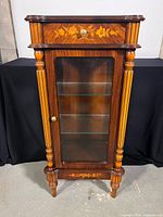 Front view of the vintage vitrine cabinet displaying marquetry details and glass front panel.