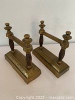 Front angled view showing both brass bookends, highlighting rectangular bases and vertical posts with finials.