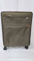 Front view of olive Briggs & Riley suitcase showing front zip pocket and spinner wheels