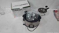Slow cooker with glass lid inside pot next to original box and OXO sifter