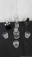 All items overview: flask, mixing pitcher with stir rod, shaker, decanter, three tumblers on black surface