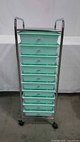 Front view showing chrome frame and 10 mint green drawers on casters